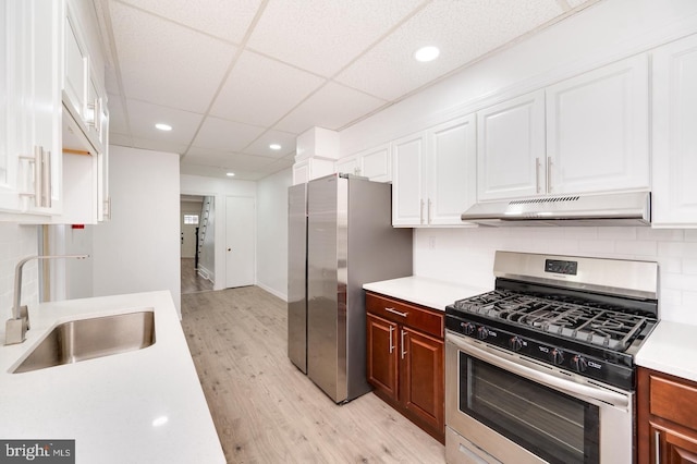 kitchen featuring under cabinet range hood, appliances with stainless steel finishes, light countertops, and a sink