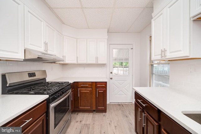 kitchen featuring gas stove, under cabinet range hood, white cabinets, and light countertops