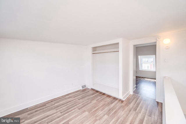 unfurnished bedroom featuring a closet, baseboards, visible vents, and light wood finished floors