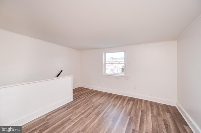 spare room featuring baseboards, wood finished floors, and ornamental molding