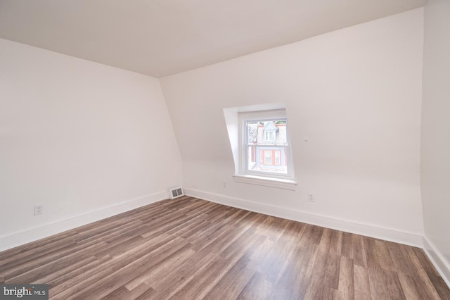 unfurnished room featuring visible vents, baseboards, and wood finished floors