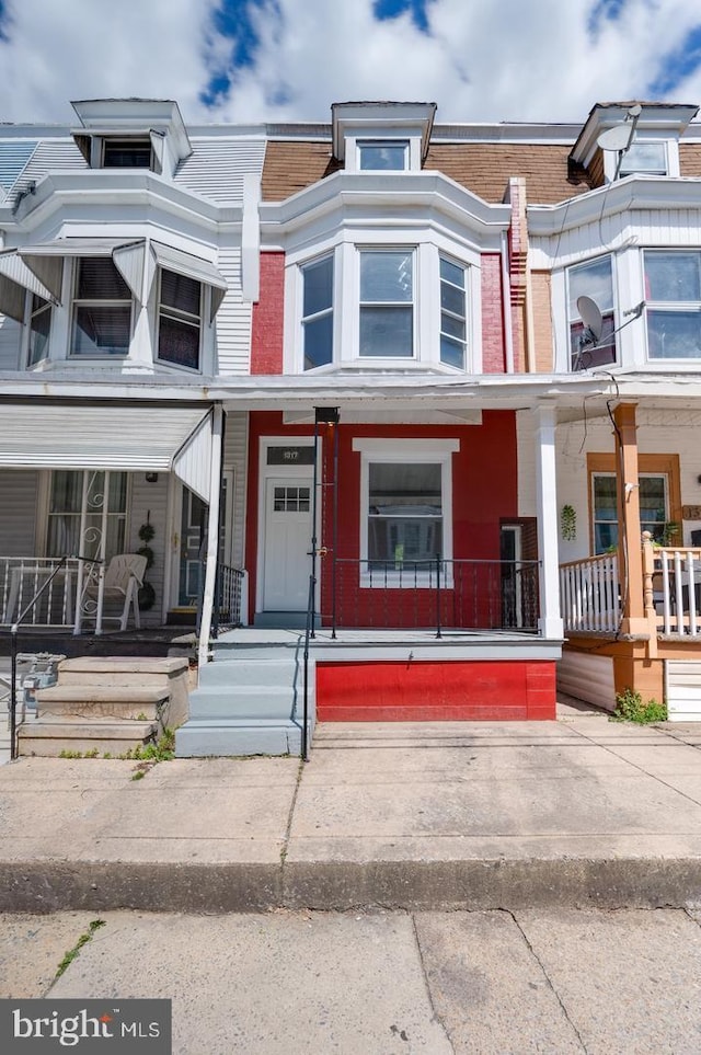 townhome / multi-family property featuring mansard roof and covered porch