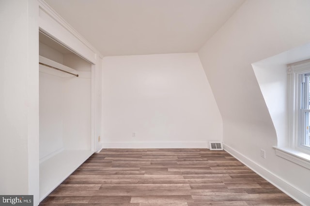 unfurnished bedroom with wood finished floors, visible vents, a closet, and baseboards