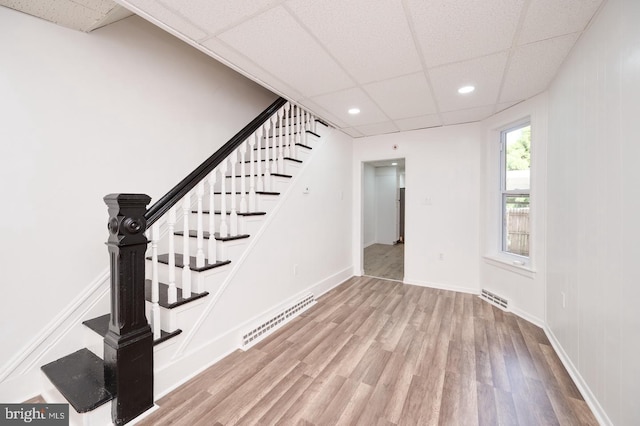 interior space with a paneled ceiling, wood finished floors, visible vents, and baseboards