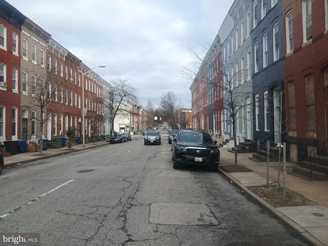 view of street with entry steps, curbs, street lighting, and sidewalks