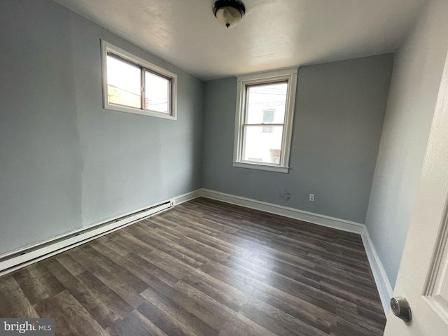 spare room with a baseboard heating unit, baseboards, a healthy amount of sunlight, and dark wood-style floors