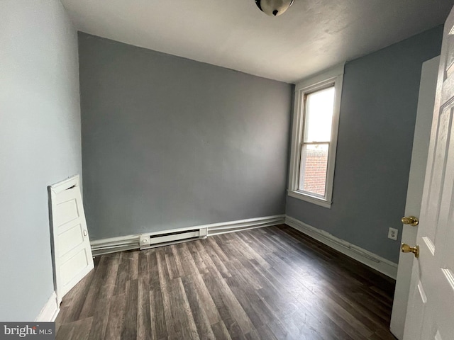 empty room with wood finished floors, baseboards, and a baseboard radiator