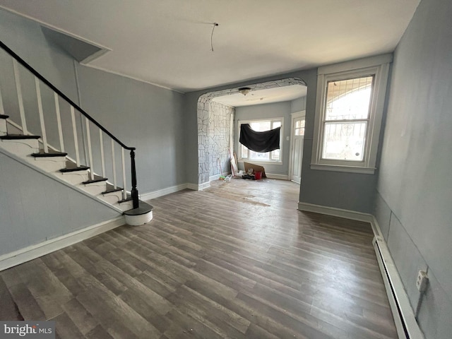 foyer with a baseboard heating unit, stairway, wood finished floors, and baseboards