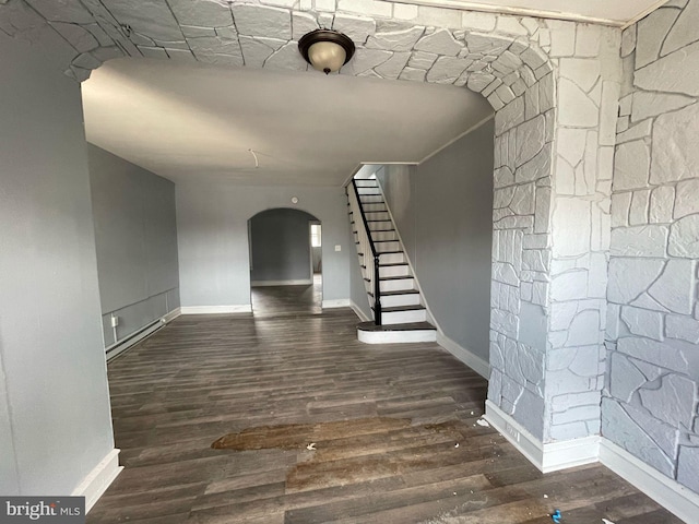 interior space featuring stairway, arched walkways, baseboards, and dark wood finished floors