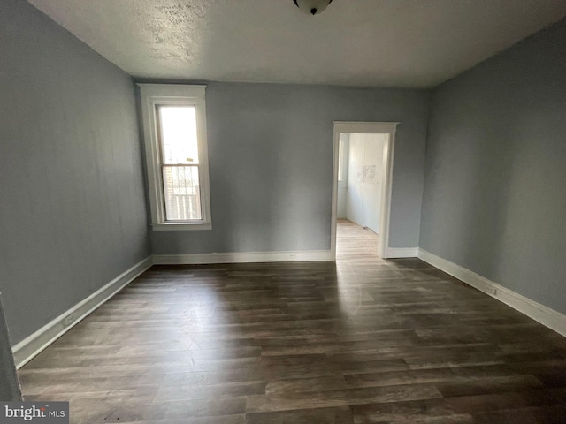 empty room featuring baseboards and dark wood-style floors