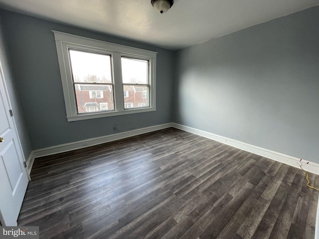 unfurnished room featuring baseboards and dark wood-style floors