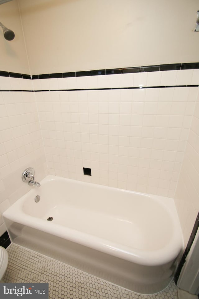 full bathroom featuring tile patterned flooring, a washtub, and toilet