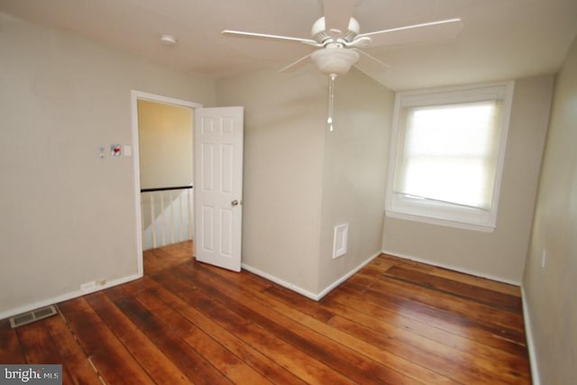 spare room featuring hardwood / wood-style floors, a ceiling fan, visible vents, and baseboards