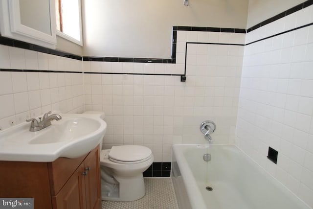 bathroom with toilet, vanity, a bathtub, tile patterned floors, and tile walls