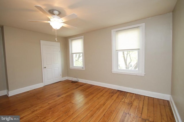 spare room featuring light wood-style flooring, a ceiling fan, and baseboards