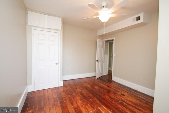 unfurnished bedroom with dark wood finished floors, baseboards, visible vents, and a ceiling fan