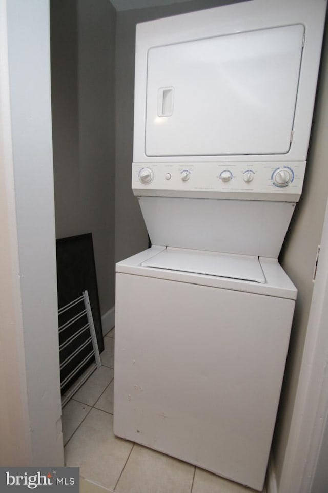 clothes washing area with laundry area, stacked washer / dryer, and light tile patterned floors