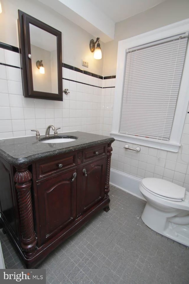 bathroom featuring toilet, tile walls, and vanity