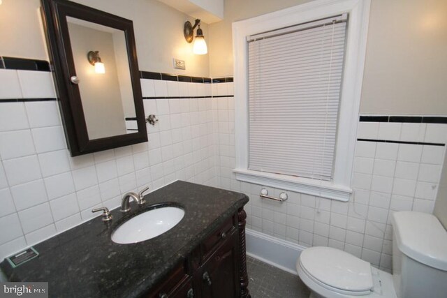 bathroom featuring toilet, tile walls, and vanity