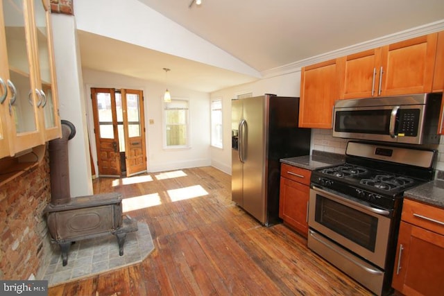 kitchen with tasteful backsplash, lofted ceiling, brown cabinets, stainless steel appliances, and wood-type flooring