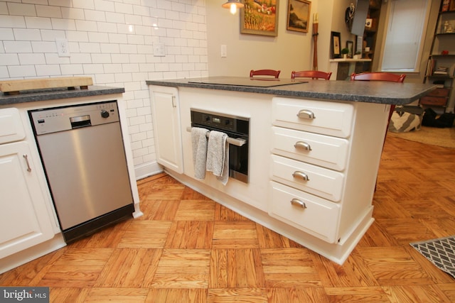 kitchen with dark countertops, wall oven, dishwashing machine, a peninsula, and white cabinetry