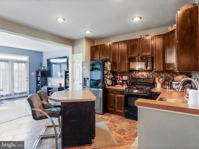 kitchen featuring a kitchen island, light countertops, a sink, and black appliances