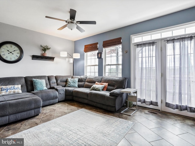 living area with a ceiling fan, visible vents, and tile patterned floors