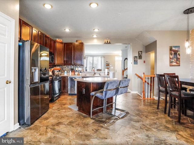 kitchen featuring a breakfast bar area, stainless steel appliances, a sink, a kitchen island, and tasteful backsplash