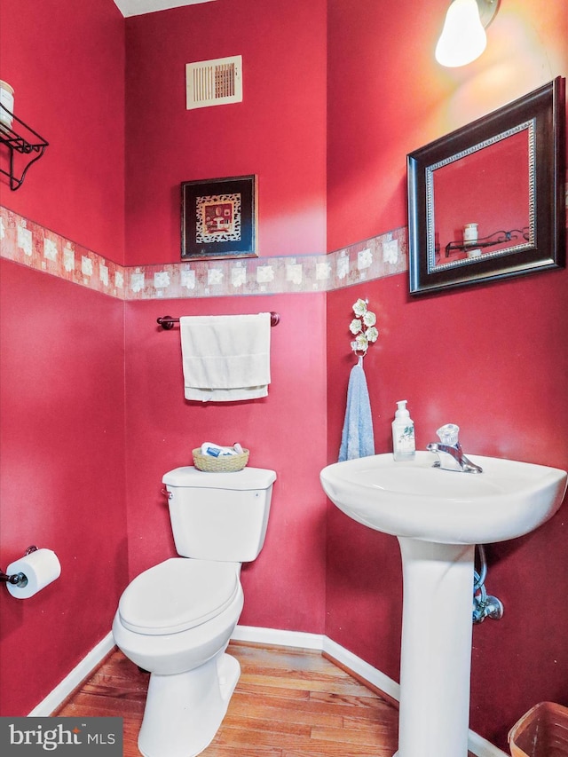 bathroom with toilet, wood finished floors, visible vents, and baseboards