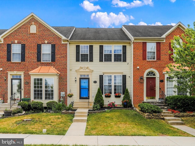 view of property featuring a front yard and brick siding