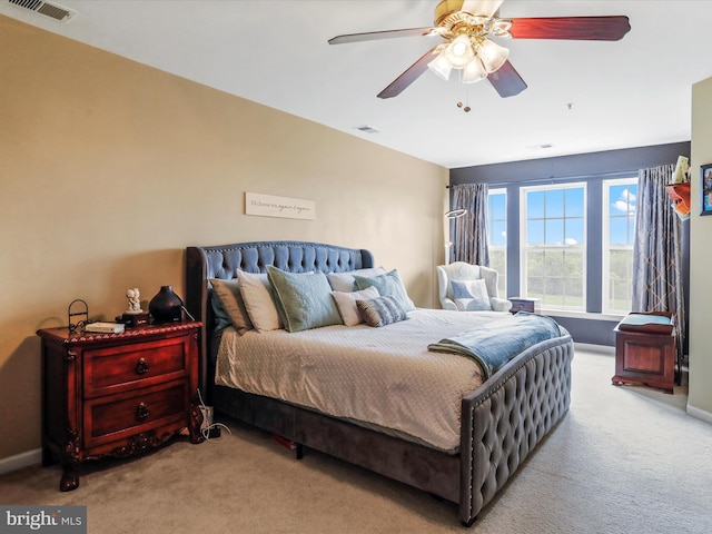 carpeted bedroom featuring a ceiling fan, visible vents, and baseboards