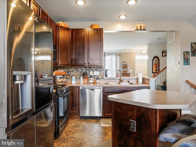 kitchen featuring stainless steel appliances, light countertops, a sink, a peninsula, and a kitchen bar