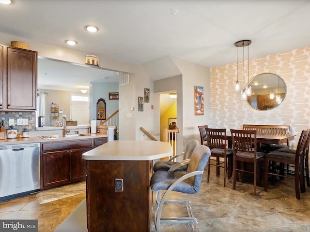 kitchen with a breakfast bar area, a sink, light countertops, stainless steel dishwasher, and a center island