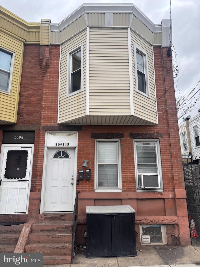 view of property with brick siding, cooling unit, and entry steps