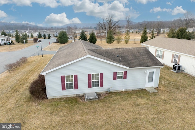 rear view of property with a shingled roof, a lawn, cooling unit, and a residential view