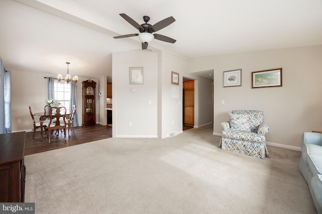 sitting room featuring vaulted ceiling, ceiling fan with notable chandelier, carpet flooring, and baseboards