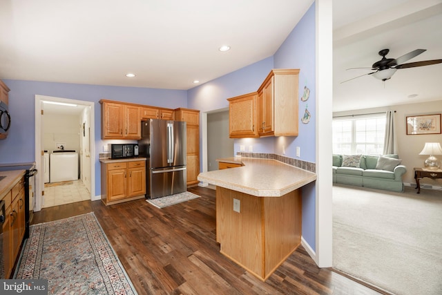 kitchen with black microwave, a peninsula, dark wood finished floors, and freestanding refrigerator