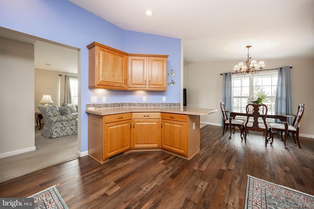 kitchen featuring baseboards, light countertops, dark wood-style flooring, and an inviting chandelier