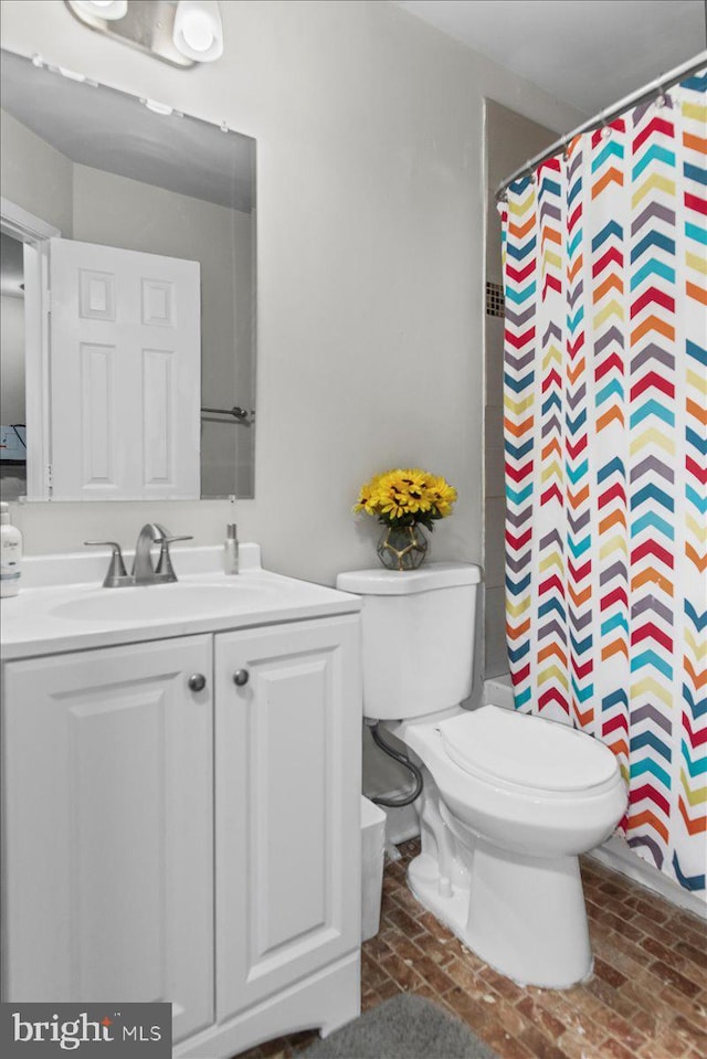 bathroom with brick floor, vanity, toilet, and a shower with curtain