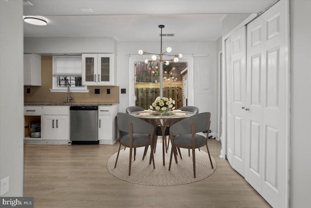 dining area with light wood-style flooring, visible vents, and a chandelier