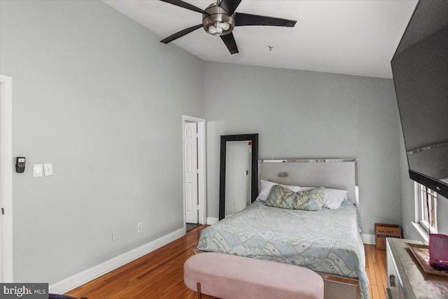 bedroom with a ceiling fan, baseboards, vaulted ceiling, and wood finished floors