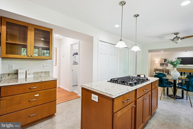 1729 Hutchinson Ln, Silver Spring, MD 20906 - kitchen with black gas stovetop, brown cabinets, glass insert cabinets, light stone counters, and ceiling fan