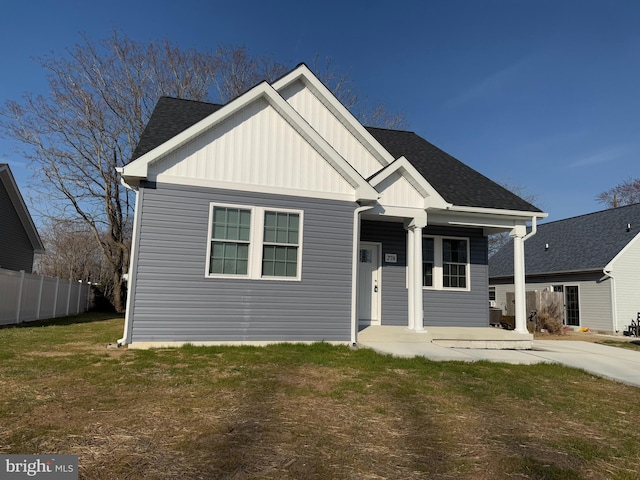 view of front of property featuring a front lawn, a porch, fence, board and batten siding, and a shingled roof