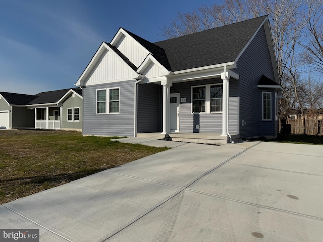 view of front facade with board and batten siding, covered porch, a front yard, and a shingled roof