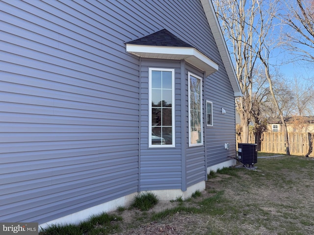 view of side of home featuring a yard, central AC unit, and fence