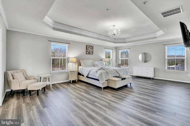 bedroom with a chandelier, visible vents, a raised ceiling, and wood finished floors