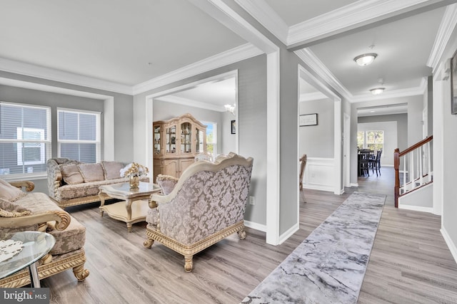 living room featuring stairs, baseboards, light wood-style floors, and crown molding