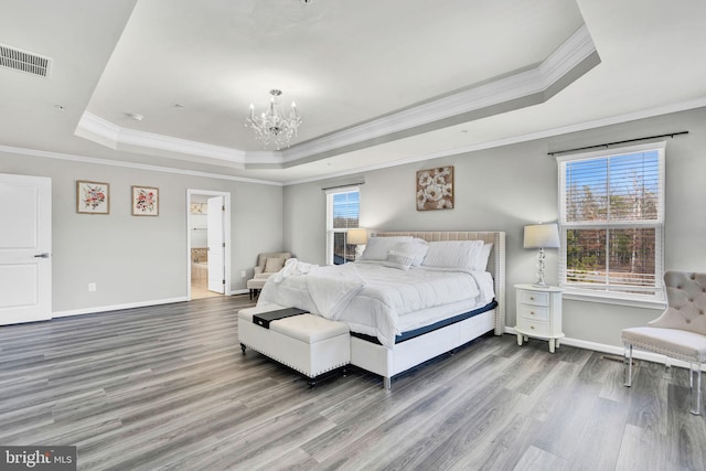 bedroom featuring visible vents, a raised ceiling, a notable chandelier, and wood finished floors