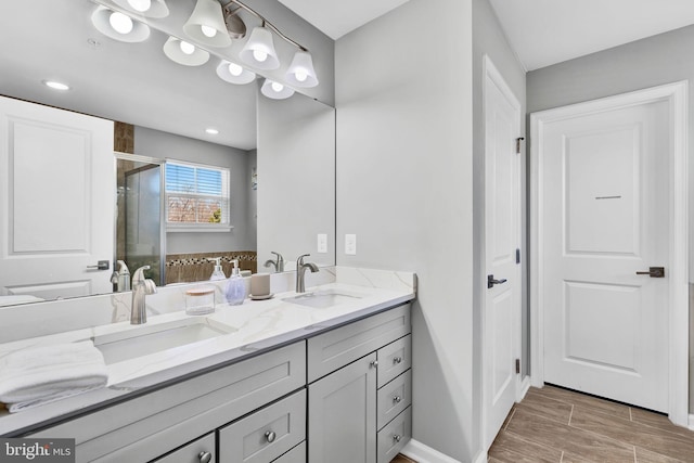 full bathroom featuring a sink, wood tiled floor, a stall shower, and double vanity