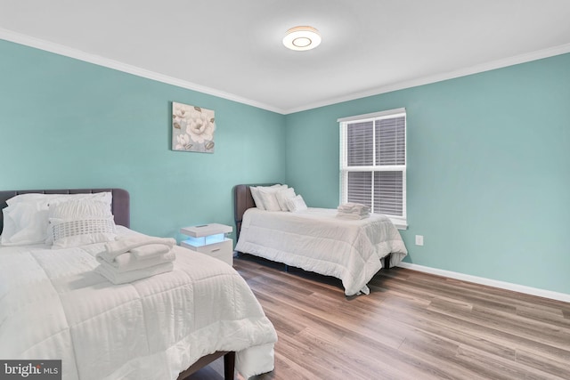 bedroom with wood finished floors, baseboards, and ornamental molding